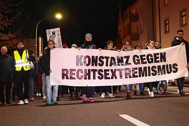 Zu sehen ist der Anfang eines Demonstrationszuges am Abend. Mehrere Personen halten gemeinsam ein breites Transparent, auf dem in großen Buchstaben "Konstanz gegen Rechtsextremismus" steht.